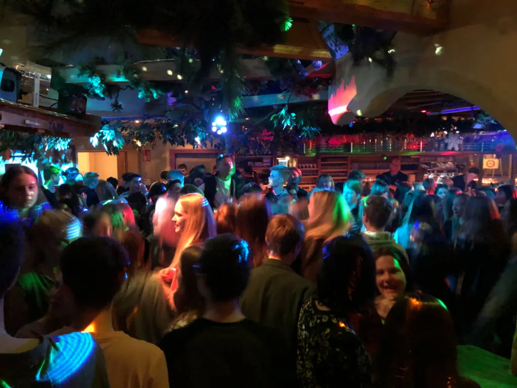 Jugendliche tanzen unter grünen Lichteffekten.
